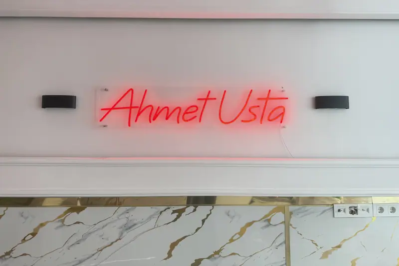 Ahmet Usta yazılı kırmızı neon, mermer duvar üzerinde