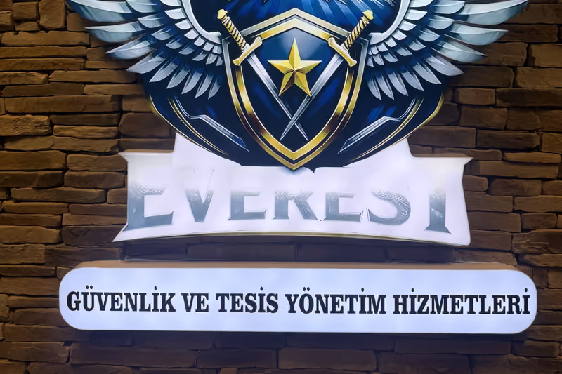 Everest Güvenlik logosunun taş duvara uygulanmış iç mekan panosu