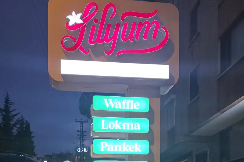 Lilyum işletmesinin yol kenarındaki ışıklı pilon totemi, gece görünümü